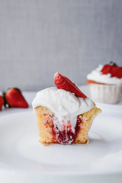 Half muffin stuffed with strawberries on white plate