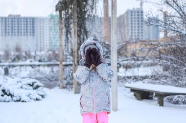 Büyük anne eldivenli bir kız kışın sokakta yüzünü kapatır.