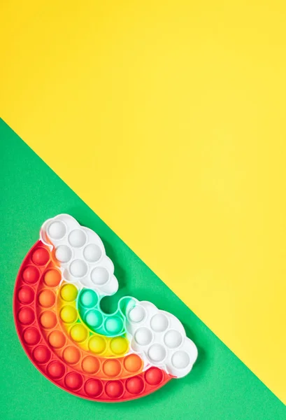 五颜六色的硅胶玩具的反应力弹出它的形状彩虹与云在绿色的黄色对角线背景 — 图库照片