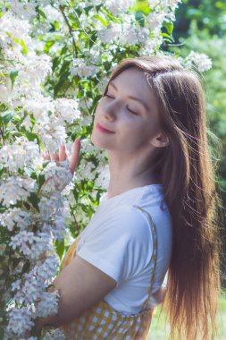 Çiçekli Weigela dalları arasında beyaz tişörtlü güzel bir esmer kızın portresi.