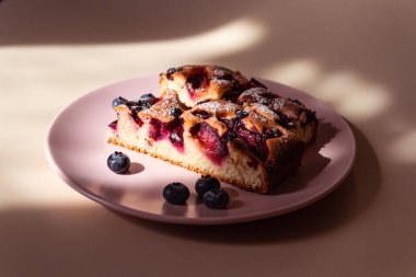 Açık meyveli turta, erikli, yaban mersinli ve siyah üzümlü ışık demetinde ve zıt gölgelerde