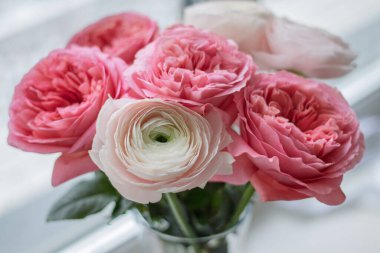 Romantik buket pembe Austin gülleri ve cam vazoda beyaz ranunculus.