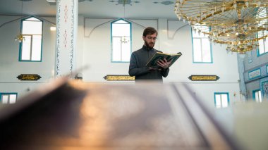 Müslüman genç adam Ramazan 'da camide Kuran okuyor. Genç Müslüman âlimin Mescidi 'nde kutsal kitabı okuması. Haram ay, ramazan ayıdır. Ramazan atmosferi. Din kavramları.