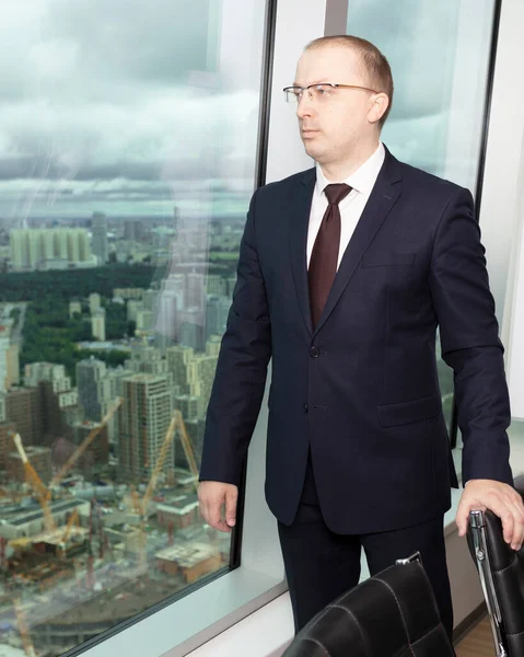 Mavi takım elbiseli yönetici şehrin etrafına bakıyor. İnşaat alanının üst katındaki ofisin kendine güveni tam, kapat.