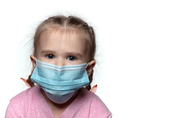 Saçları örgülü ve mavi tıbbi maske takan sevimli Avrupalı kız kameraya doğru bakıyor.