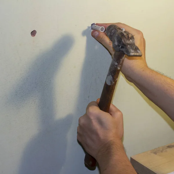 Hammering of a wall plug or Rawlplug. Square image