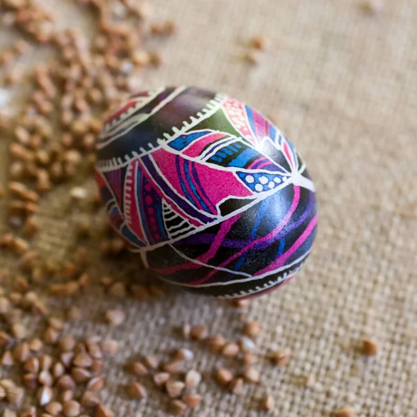 Easter egg with folklore ornament on canvas with buckwheat. Easter illustration in Ukrainian folk style.