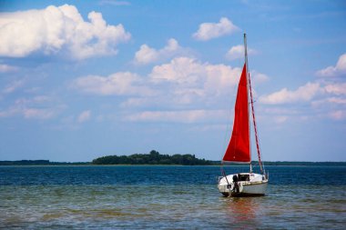Büyük gölde kırmızı yelkenli küçük yelkenli.