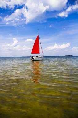 Gölde kırmızı yelkenli küçük yelkenli