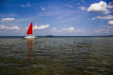 Kırmızı yelkenli tek direkli yelkenli.