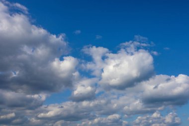 Pofuduk beyaz kümülüs bulutları açık ve güneşli bir günde masmavi bir gökyüzünde.