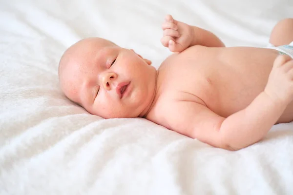 Ein Neugeborenes liegt auf einer weißen Decke. Nahaufnahme Porträt eines Kindes. — Stockfoto