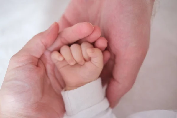 Föräldrar håller i handen på sitt nyfödda barn i sina armar.Händer på nära håll — Stockfoto