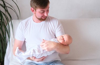 Bir baba üç aylık oğlunu kollarına alır.