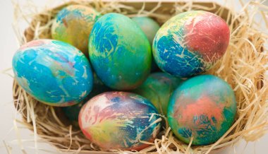 Çok renkli Paskalya yumurtaları masanın üzerindeki sepetin içinde, yakın plan.