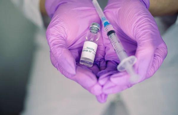 Female hands in gloves hold coronavirus vaccine and syringe for injection. Covid-19 concept, pandemic, vaccination