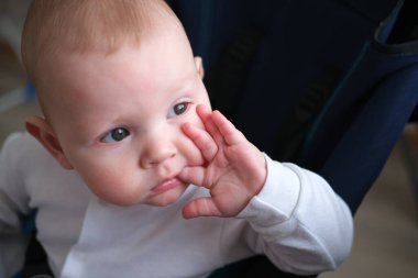 Çocuğun alerjisi ve ilk dişleri var. Bebek arabasında oturan bir çocuğun portresi.