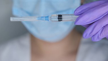 Eldivendeki kadın ellerde koronavirüs aşısı ve şırınga bulunur. Covid-19 konsepti, salgın hastalık, aşı