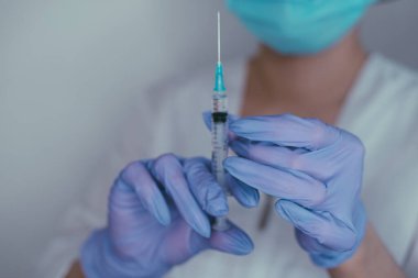 Eldivendeki kadın ellerde koronavirüs aşısı ve şırınga bulunur. Covid-19 konsepti, salgın hastalık, aşı