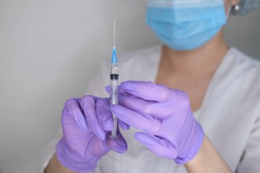 Eldivendeki kadın ellerde koronavirüs aşısı ve şırınga bulunur. Covid-19 konsepti, salgın hastalık, aşı