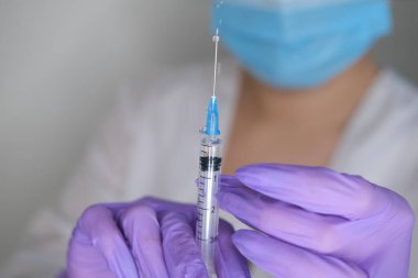 Eldivendeki kadın ellerde koronavirüs aşısı ve şırınga bulunur. Covid-19 konsepti, salgın hastalık, aşı