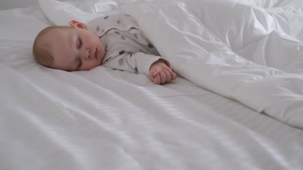 De zogende baby slaapt op wit beddengoed in het bed. — Stockvideo