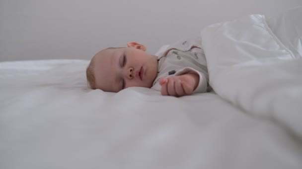 De zogende baby slaapt op wit beddengoed in het bed. — Stockvideo
