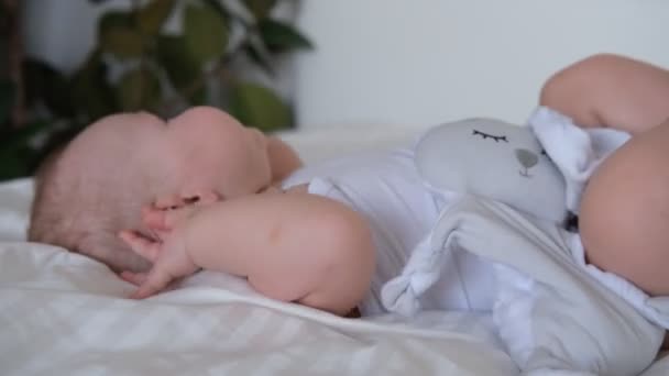 Um bebê que amamenta dorme em uma cama em lençóis brancos. — Vídeo de Stock