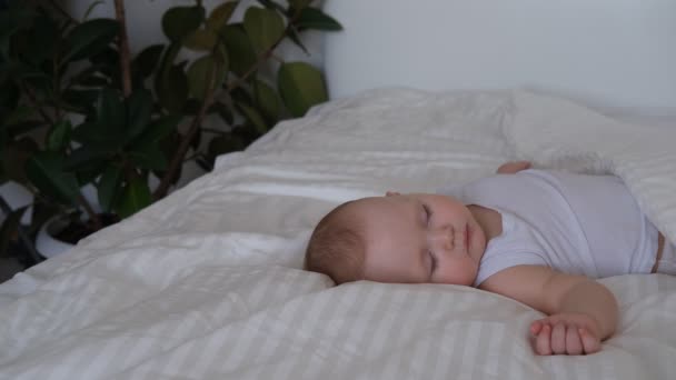 A nursing baby sleeps in a bed on white linens. — Stock Video