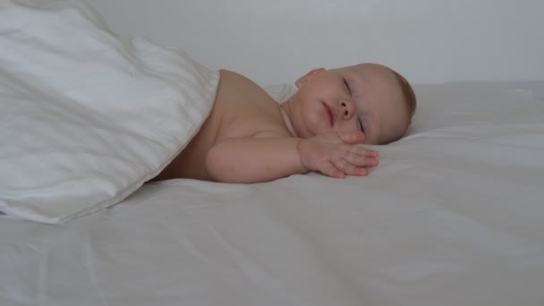 Little sleeping baby lies on white bedding — Stock Video