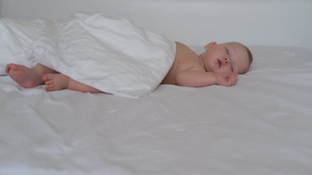 Little sleeping baby lies on white bedding — Stock Video