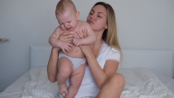 Een jonge moeder wiebelt de baby in haar armen. De baby huilt en wil niet slapen. — Stockvideo