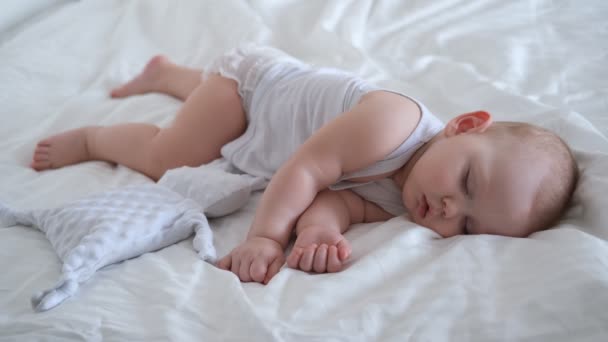 一个小孩睡在白色的床上 一个睡在白色背景上的小男孩的画像 — 图库视频影像