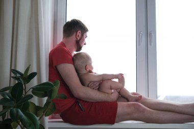 Baba çocuğu kollarına alır, pencereden dışarı bakarlar.