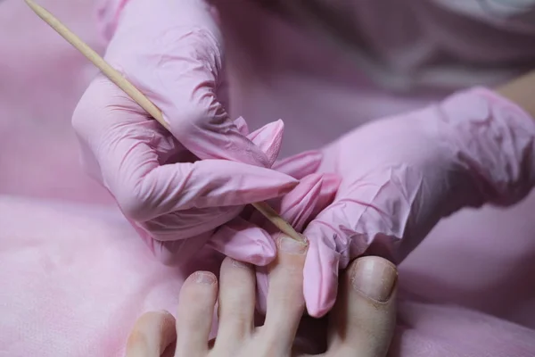 Professional hardware pedicure on an electric machine. Peeling of feet with a special electrical device. Foot care in the SPA salon.