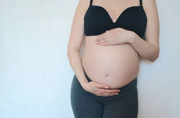 Uma Mulher Grávida Coloca Contra Uma Parede Branca Acaricia Sua — Fotografia de Stock