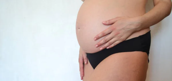 Беременная Женщина Нижнем Белье Стоит Фоне Белой Стены Гладит Себя — стоковое фото