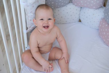 Çocuk beşiğinde oturuyor ve gülümsüyor.. 