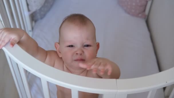 Gros plan d'un petit enfant debout dans un berceau. Le tout-petit ne veut pas dormir dans le lit. — Video