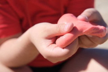  Elinde parlak kırmızı balçık tutan genç bir kız. Eğitim, yaratıcılık, çocukluk kavramı. Seçici odak.
