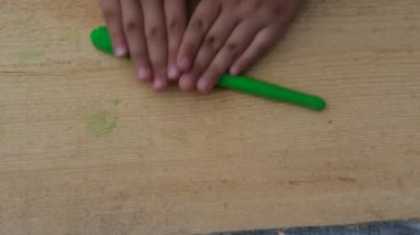 Çocuk yumuşak çok renkli plastikten ahşap bir tahta üzerinde çeşitli figürler yontuyor. Yakın plan.