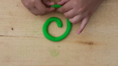 Çocuk yumuşak çok renkli plastikten ahşap bir tahta üzerinde çeşitli figürler yontuyor. Yakın plan.