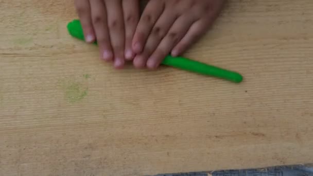 Ребенок делает различные фигуры на деревянной доске из мягкого разноцветного пластилина. Крупный план — стоковое видео