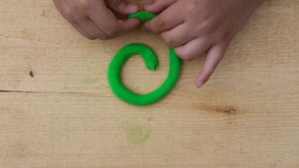 A criança esculpe vários números em uma tábua de madeira da plasticina multicor suave. Close-up — Vídeo de Stock