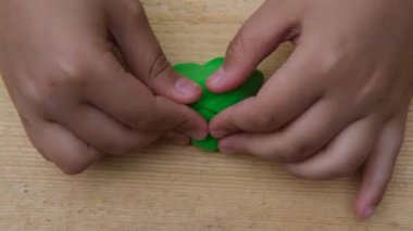 Çocuk yumuşak çok renkli plastikten ahşap bir tahta üzerinde çeşitli figürler yontuyor. Yakın plan.