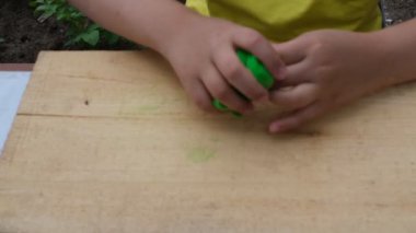 Çocuk yumuşak çok renkli plastikten ahşap bir tahta üzerinde çeşitli figürler yontuyor. Yakın plan.