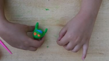 Çocuk yumuşak çok renkli plastikten ahşap bir tahta üzerinde çeşitli figürler yontuyor. Yakın plan.