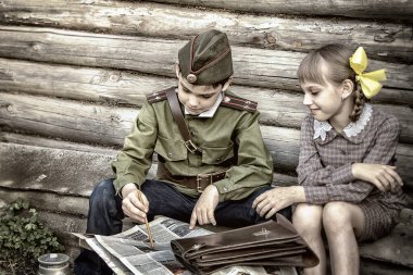 Zafer Günü için klasik olarak stilize edilmiş kartpostal. Askeri üniformalı bir çocuk ve eski elbiseli bir kız. 9 Mayıs, Rusya 'da Zafer Günü teması. Yumuşak seçici odak, eklenen gürültü.