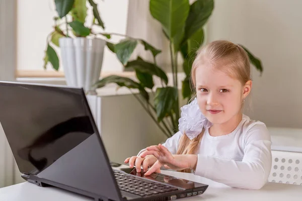 The girl learns (communicates, talks) through a computer / laptop