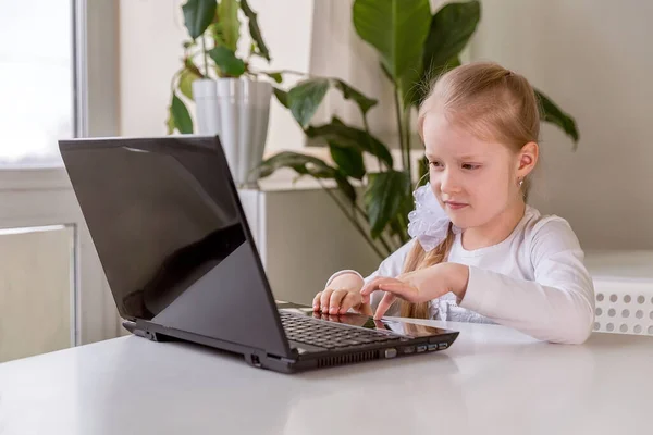 The girl learns (communicates, talks) through a computer / laptop